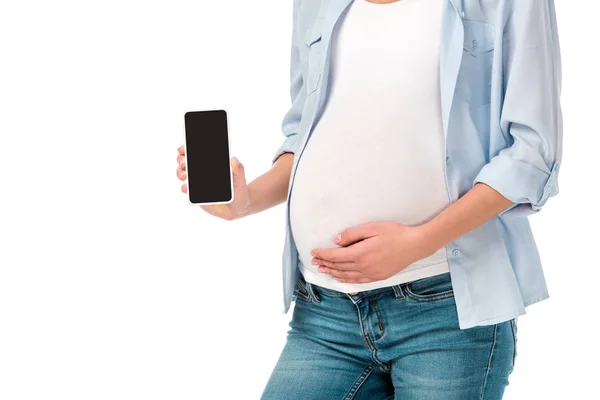 Vista recortada de la mujer embarazada que presenta teléfono inteligente con pantalla en blanco aislado en blanco - foto de stock