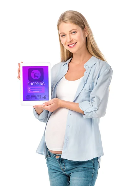 Mujer embarazada sonriente mostrando tableta digital con aparato de compras aislado en blanco - foto de stock