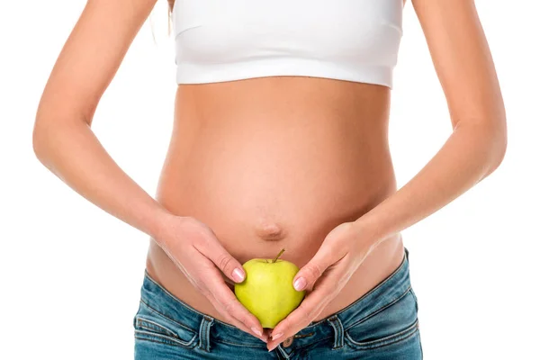 Abgeschnittene Ansicht einer schwangeren Frau, die einen gesunden Apfel in der Nähe ihres Bauches hält, isoliert auf weiß — Stockfoto
