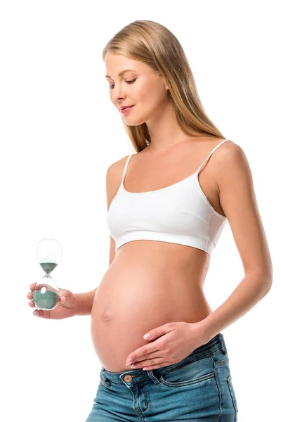 Schöne schwangere Frau hält Sanduhr isoliert auf weiß — Stockfoto
