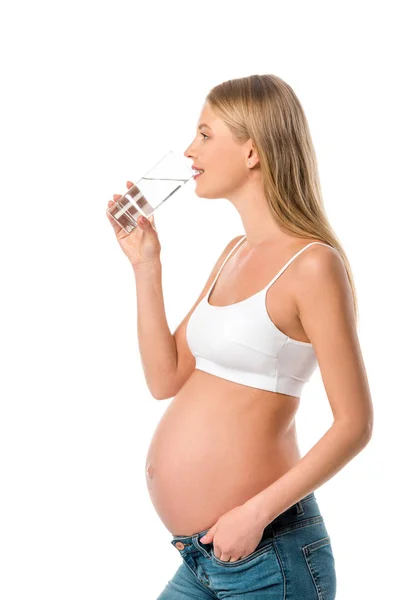 Mujer embarazada en sujetador blanco beber agua limpia de vidrio aislado en blanco - foto de stock