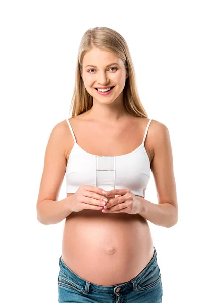 Усміхнена вагітна жінка тримає склянку чистої води ізольовано на білому — стокове фото