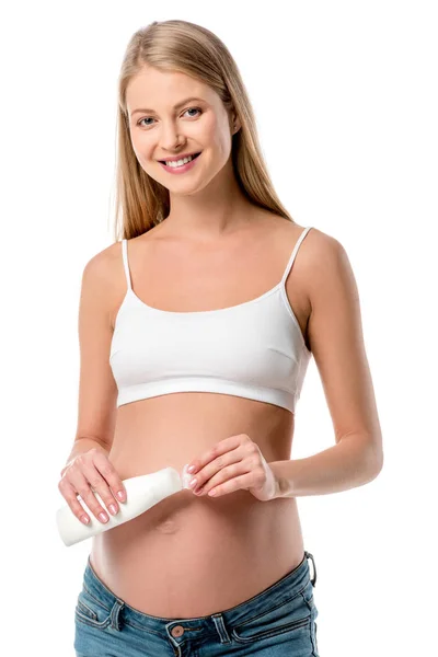 Красива вагітна жінка в білому бюстгальтері тримає пляшку лосьйону ізольовано на білому — стокове фото