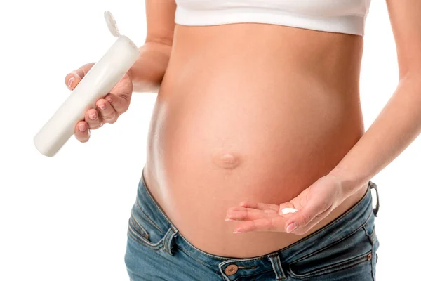Обрізаний вид вагітної жінки, що наносить косметичний лосьйон на животик, щоб уникнути розтяжок ізольованих на білому — стокове фото