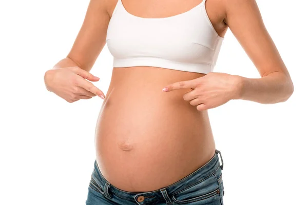 Обрезанный вид беременной женщины, указывающей на ее живот изолированный на белом — стоковое фото