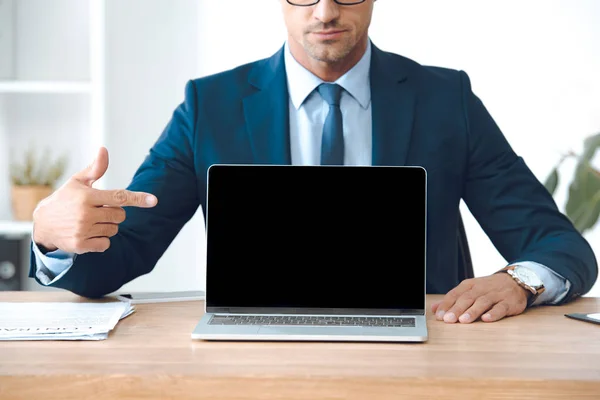 Plan recadré de l'homme d'affaires pointant avec le doigt à l'ordinateur portable avec écran blanc — Photo de stock