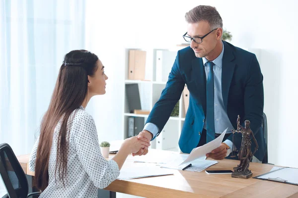 Professional lawyer and young female client shaking hands in office — Stock Photo