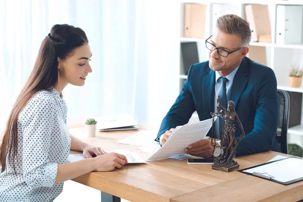 Smiling lawyer showing papers to happy client in office — Stock Photo