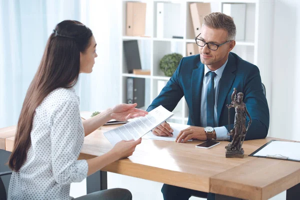 Advogado e cliente olhando uns para os outros durante a discussão de papéis no escritório — Fotografia de Stock