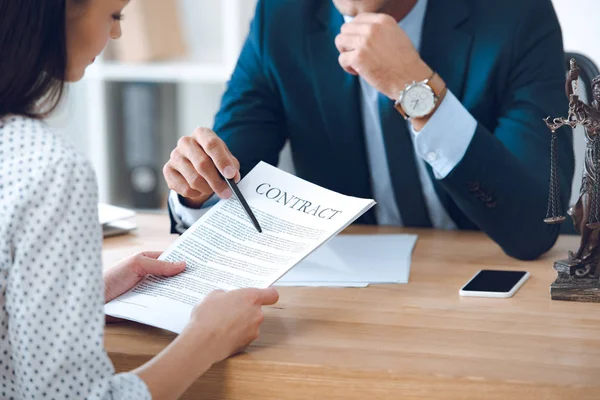 Plan recadré d'une femme tenant des papiers et un avocat pointant avec un stylo au contrat — Photo de stock