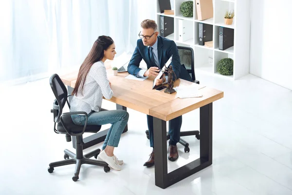 Aus der Vogelperspektive: Anwalt zeigt auf Klemmbrett und arbeitet mit junger Frau im Büro — Stockfoto