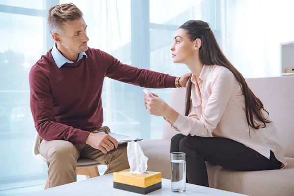 Psychotherapist and upset patient looking at each other while sitting on office during therapy — Stock Photo
