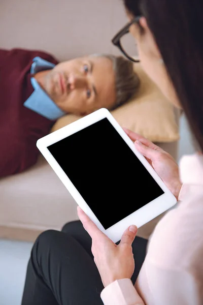 Cropped shot of psychologist using digital tablet with blank screen and patient lying on couch — Stock Photo