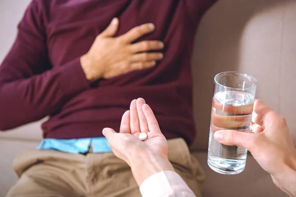 Plan recadré de psychothérapeute donnant un verre d'eau et de pilule au patient souffrant de chagrin cardiaque — Photo de stock