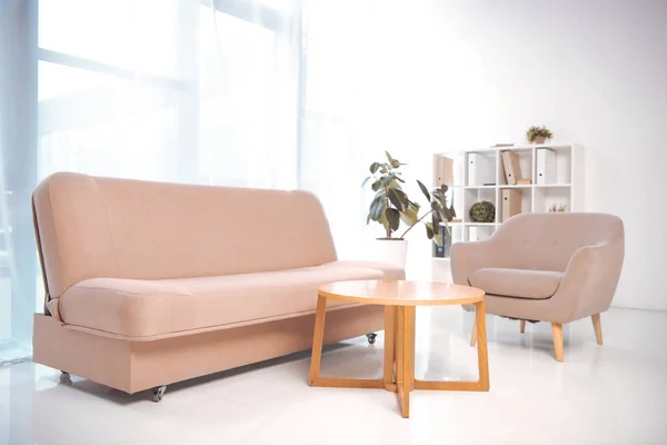 Canapé, fauteuil, table basse et bibliothèque avec des dossiers dans un bureau vide — Photo de stock