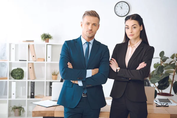 Retrato de empresarios con los brazos cruzados de pie en el lugar de trabajo en la oficina - foto de stock