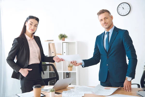 Donna d'affari che dà il documento a collega a posto di lavoro in ufficio — Foto stock