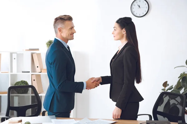 Side view of business colleagues shaking hands at workplace in office — Stock Photo
