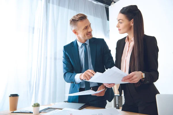 Lächelnde Geschäftskollegen beim Papierkram am Arbeitsplatz im Büro — Stockfoto