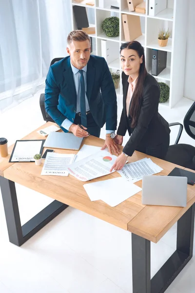 Vista de ángulo alto de colegas de negocios haciendo papeleo en el lugar de trabajo en la oficina - foto de stock