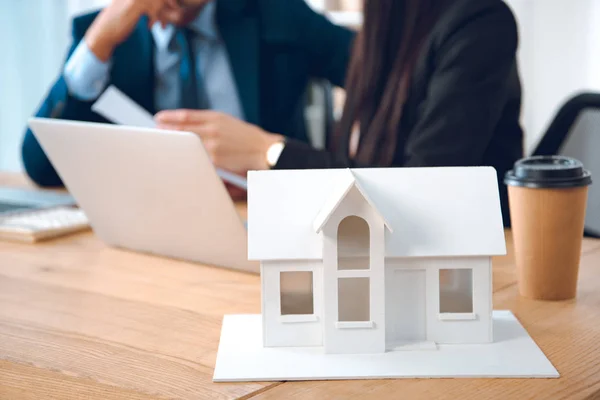 Visione parziale degli agenti assicurativi sul posto di lavoro con modello di casa in ufficio, concetto di assicurazione casa — Foto stock