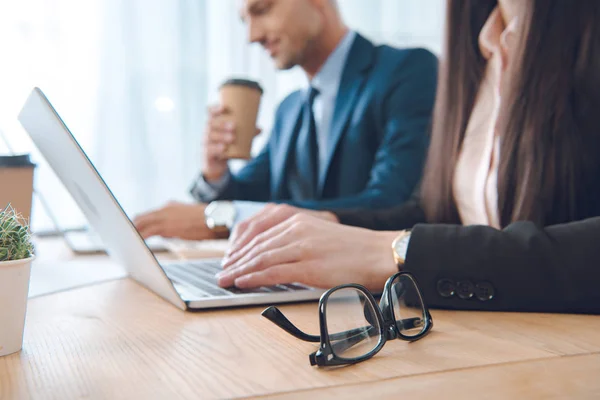 Visión parcial de los empresarios que trabajan en ordenadores portátiles en el lugar de trabajo en la oficina - foto de stock