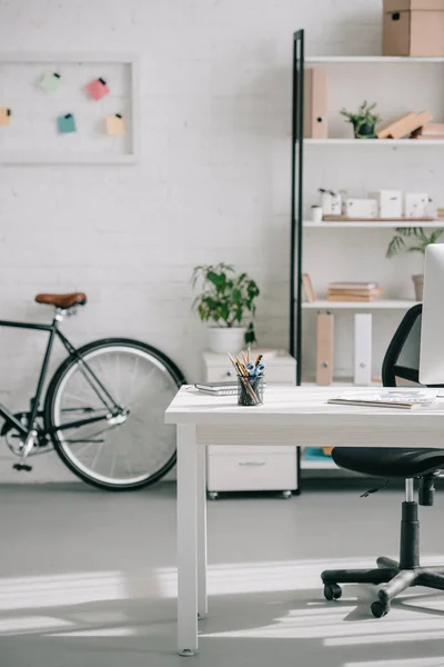 Vélo, étagères et table dans un bureau d'affaires moderne — Photo de stock
