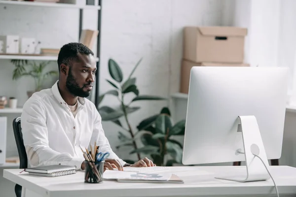 Bel homme d'affaires afro-américain regardant l'ordinateur dans le bureau — Photo de stock