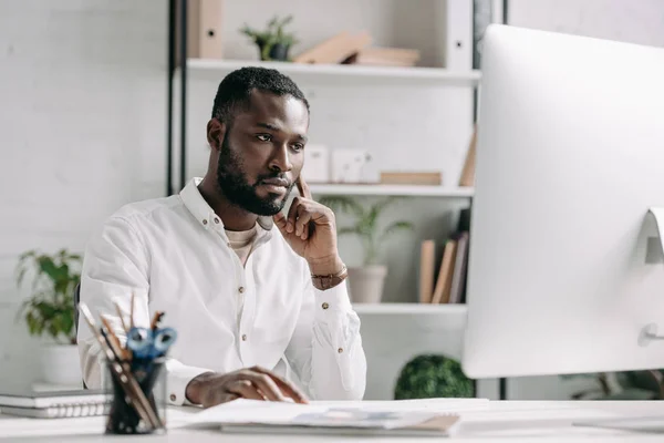 Серьезный красивый африканский бизнесмен, работающий за компьютером в офисе — стоковое фото