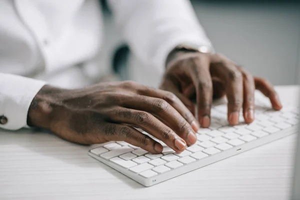 Abgeschnittenes Bild eines afrikanisch-amerikanischen Geschäftsmannes, der im Büro auf der Computertastatur tippt — Stockfoto