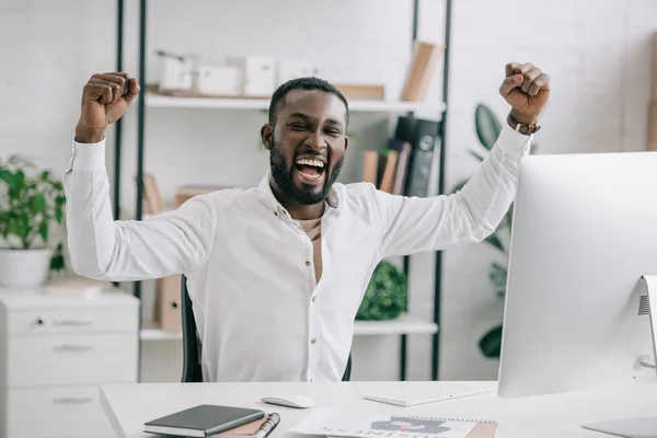 Emocionado empresario afroamericano gritando y mostrando sí gesto en la oficina. El hombre celebra ganar una apuesta con un juego, apuesta de fútbol, apuestas deportivas — Stock Photo