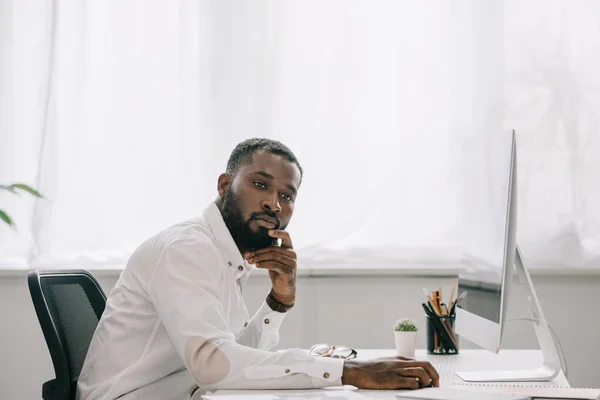 Вид збоку красивий афро-американських бізнесмена працює за комп'ютером в офісі і дивитися вбік — стокове фото