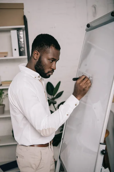 Schöner afrikanisch-amerikanischer Geschäftsmann schreibt im Büro auf Flipchart — Stockfoto