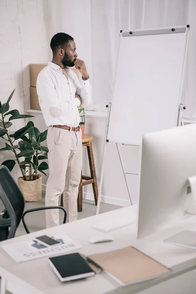 Schöner nachdenklicher afrikanisch-amerikanischer Geschäftsmann schaut im Büro auf Flipchart — Stockfoto