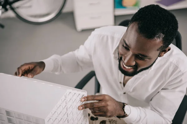 High angle view of smiling handsome african american architect looking at architecture model in office — Stock Photo