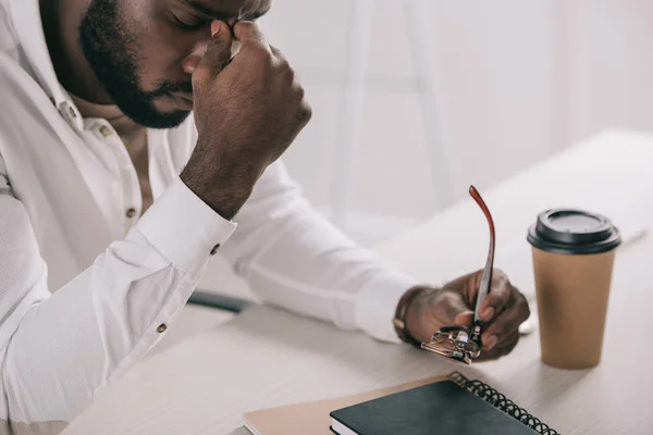Cansado Africano americano empresário tocando nariz ponte e segurando óculos no escritório — Fotografia de Stock