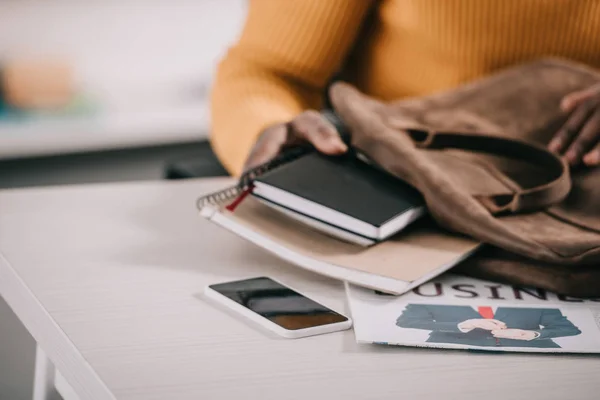 Обрезанный образ африканского американского дизайнера положить ноутбуки в портфель в офисе — стоковое фото
