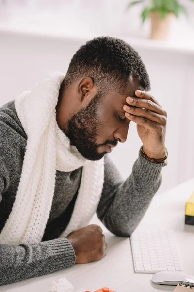 Cansado joven afroamericano hombre con dolor de cabeza sentado en la oficina - foto de stock