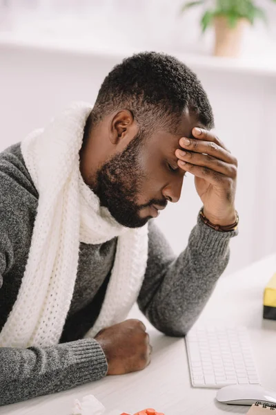 Fatigué jeune homme afro-américain avec mal de tête assis au bureau — Photo de stock