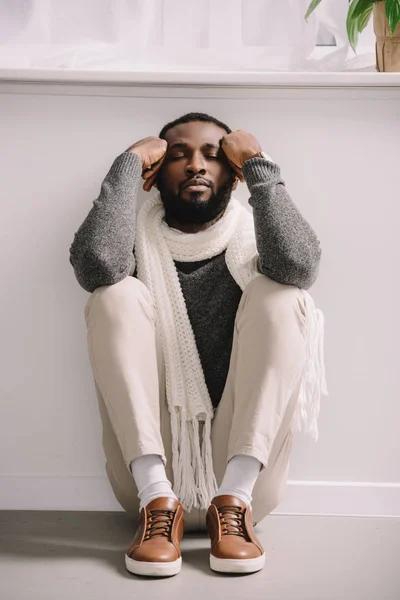 Tired ill african american man in white scarf sitting on floor — Stock Photo