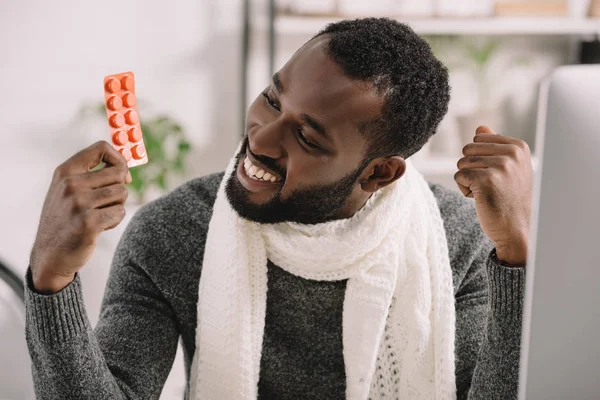 Glücklich afrikanisch-amerikanischer Mann hält Pillen im Büro mit Behandlung — Stockfoto