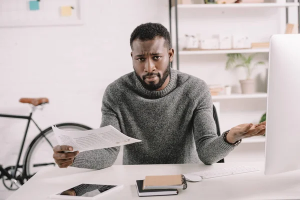 Confused bearded african american businessman with shrug gesture holding document in office — Stock Photo