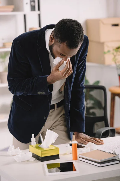 Больной бизнесмен, простуженный во время работы с цифровыми устройствами в офисе — стоковое фото