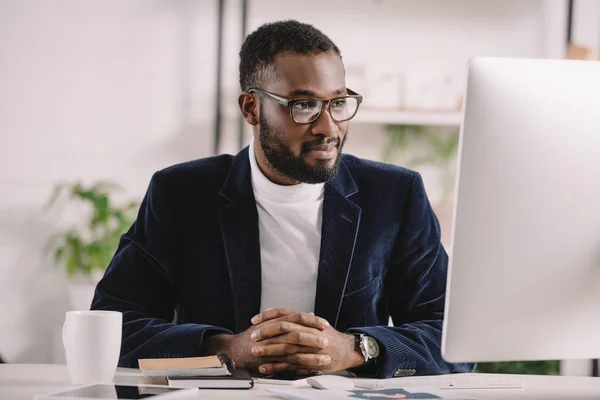 Успешный африканский американский бизнесмен, работающий с компьютером в современном офисе — стоковое фото