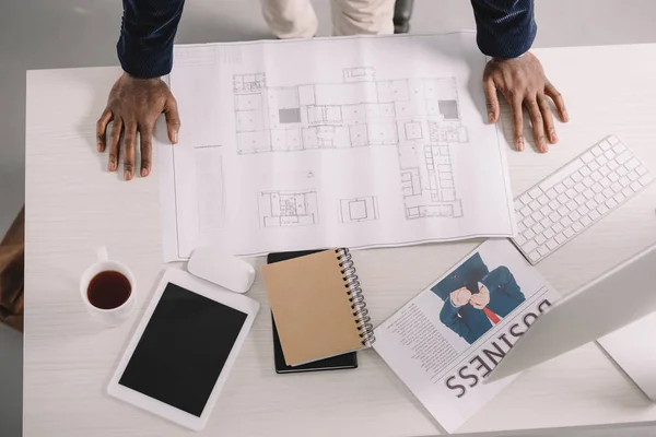 Ausgeschnittene Ansicht eines Architekten, der mit Blaupause, digitalem Tablet und Wirtschaftszeitung im Büro arbeitet — Stockfoto