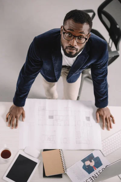 Overhead view of african american architect working with blueprint in office — Stock Photo