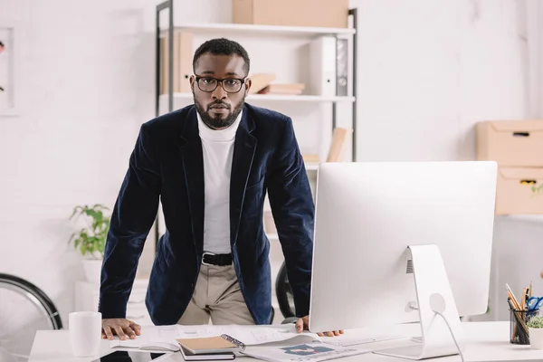 Bel architecte afro-américain travaillant avec le plan de travail à l'espace de travail avec l'ordinateur — Photo de stock