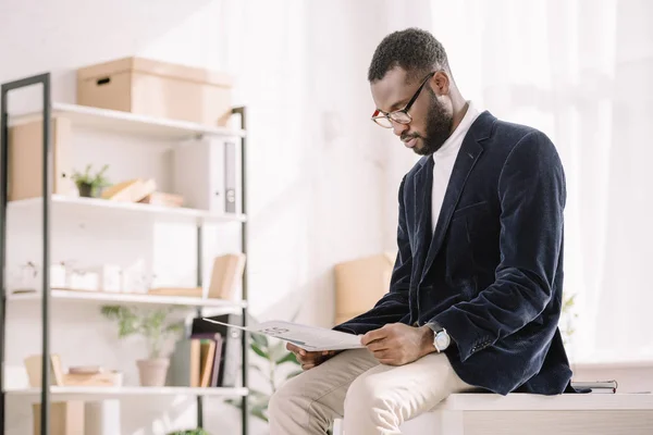 Стильний африканських американський бізнесмен в оксамит куртку, читаючи газету в офісі — стокове фото