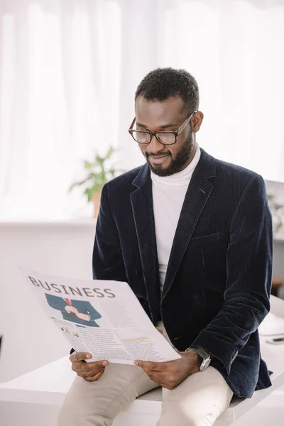 Bearded african american businessman in velvet jacket reading newspaper — Stock Photo