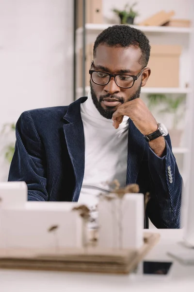 Pensive african american architect working with business buildings model — Stock Photo